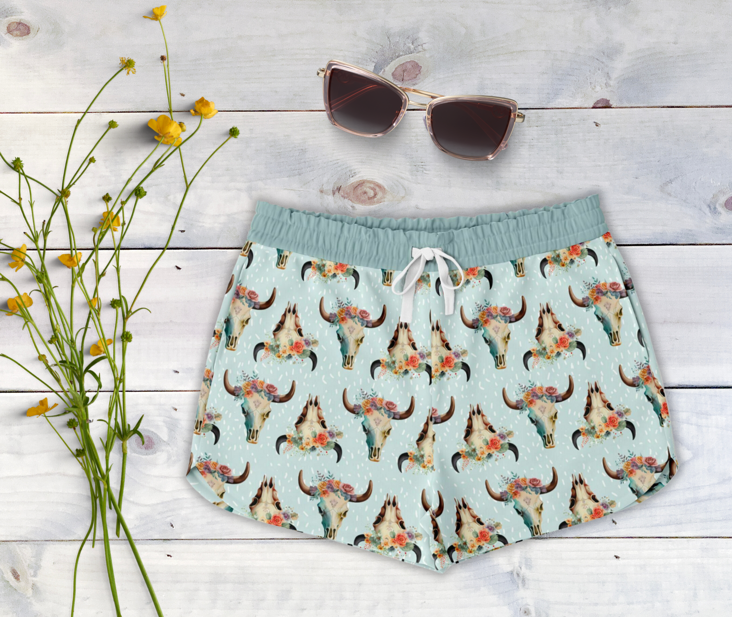 Light blue lounge shorts featuring a floral cow skull print. Shorts include a back pocket, side pockets and a white drawstring waistband.